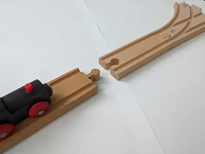Un train jouet où les voies en bois sont séparées par un espace